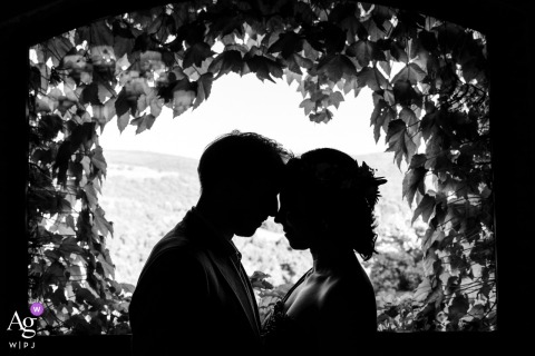 Couple poses before window at Agriturismo Casetta delle Erbe, framed by Virginia creeper and valley view.
