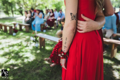 A detailed shot at the Saint-Cricq-Chalosse town hall park in France features intertwined arms and a butterfly tattoo during a heartfelt and personal outdoor wedding ceremony.