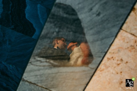 An artistic reflection of the couple is seen in a pool of water at the Domaine de la Trinité in France, creating a unique and symmetrical wedding portrait.