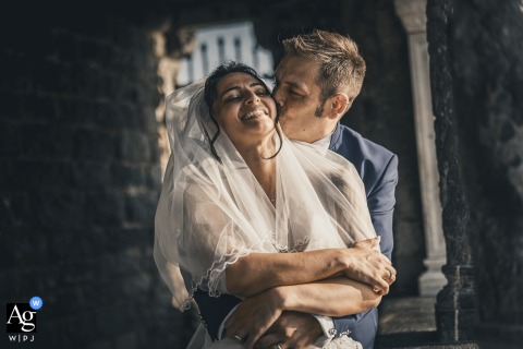 A loving embrace in Portovenere, Liguria, Italia, with him wrapping her from behind for a kiss near San Pietro.