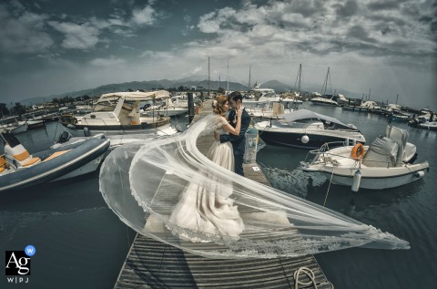 At Bocca di Magra, an artistic wedding portrait shows a veil of love enveloping the couple in a romantic embrace on the wooden boat docks.