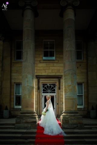 Bride stands backlit at Balbirnie House entrance, her silhouette glowing against the grand doorway.