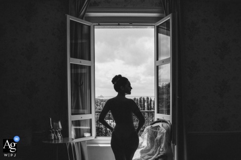  Black and white profile shot of the bride preparing in her room at Chateau les Hauts, seen at a window.