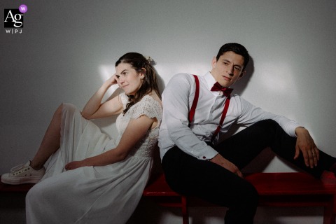 Cinematic, minimalistic wedding portrait of the bride and groom at Lyon's Club d'Aviron, featuring strong shadows, spotlight, and bold red accents.