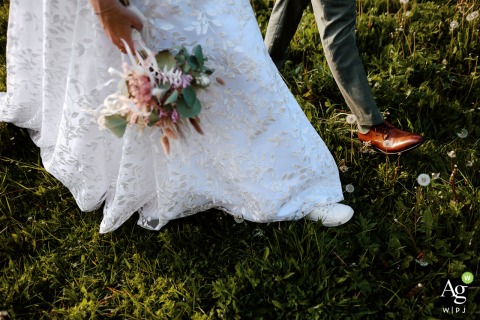 In a creative lower-body shot at Solalex, Switzerland, the bride and groom’s legs are seen walking through the grass as she carries her vibrant floral wedding bouquet.