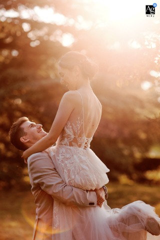 Fribourg, Switzerland: Romantic Sunset Shot of Groom Carrying Bride Fribourg, Switzerland: A backlit image of the groom carrying his bride, illuminated by the warm glow of the sunset.