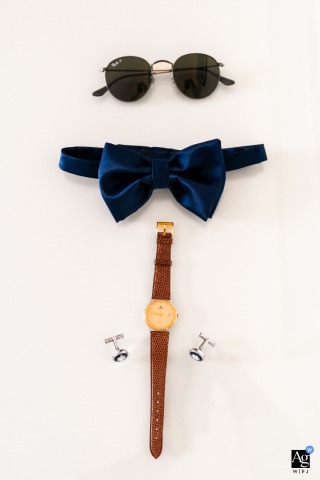 Groom's wedding day details, such as cufflinks, watch, and tie, artfully arranged in a flat lay on a white background, photographed in Udine, Italy.