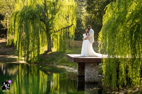 The bride and groom pose for a wedding portrait on a wooden dock over flat water at Milagro Winery, Ramona, CA.