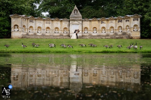 Distant Reflection of Bride and Groom at Stowe House, Full View of Structure Captured A distant reflection shot of B and G at the Stowe House, capturing the full view of the structure.
