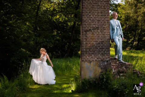 The groom stands against a pillar while his bride elegantly displays her dress, next to the LEV by Mike wedding venue.