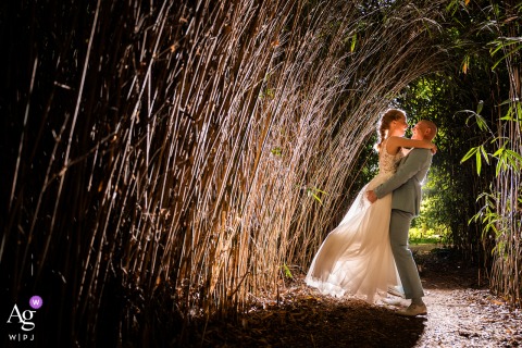 Backlit shot of the groom lifting his bride in a narrow bamboo path next to LEV by Mike wedding venue.