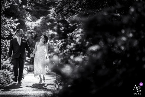 Black and white shot of a couple laughing as they walk along a path at Hendry House, Arlington, VA.