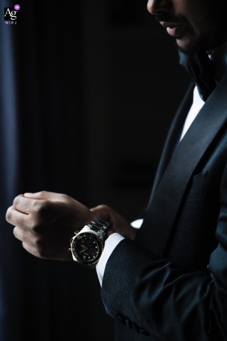 A stylistic groom detail shot shows the fine texture of the suit fabric and the classic design of a wristwatch as the man prepares inside a London, England, hotel on his wedding day.