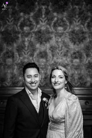 Bar George - Montreal, Quebec -  A stylish black and white portrait of the bride and groom is artistically captured within a historical room at Bar George in Montreal, Quebec, featuring intricate wallpaper backdrop.
