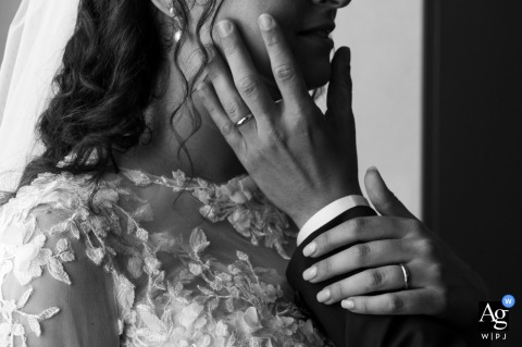 San Benedetto Po, Mantova, Italia—A tight crop of a couple's hands highlights their wedding rings as the groom gently caresses his bride on their wedding day.
