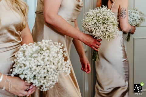 Bridesmaids hold delicate handfuls of gypsophila confetti at Hartsfield Manor in Surrey, England, preparing for the celebratory toss following the ceremony in the beautiful United Kingdom countryside.