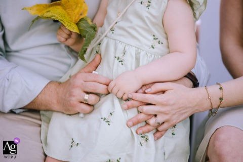 An elegant details photograph captured at Schloss Ehreshoven in Engelskirchen, Germany, shows the intertwined hands of the parents holding their daughter's hand during the wedding ceremony.