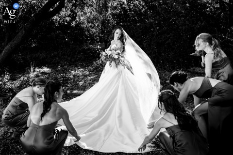 Bridesmaids Adjust Gown In Black And White Portrait At Samoset Resort Maine Wedding Samoset Resort, Maine, provides the backdrop for a black-and-white portrait as the bride stands ready while her bridesmaids carefully adjust the flowing fabric of her gown.