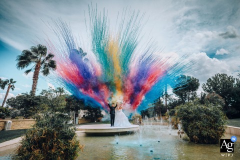 The Giardino del Mago reception venue is set against a vibrant burst of colored smoke surrounding the newlyweds, creating an artistic and dramatic scene setter.