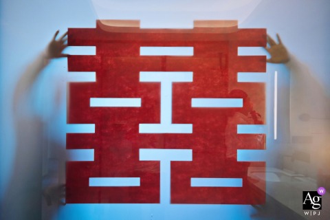 An elegant detail shot from a Nanping, Fujian hotel shows a Chinese character being carefully applied to a window during the getting ready portion of a wedding day.