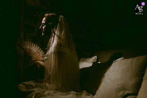 In Casteljaloux, Lot et Garonne, France, a sunlit profile portrait captures the bride sitting quietly during her preparations, enveloped in the warm, diffused light of the summer.