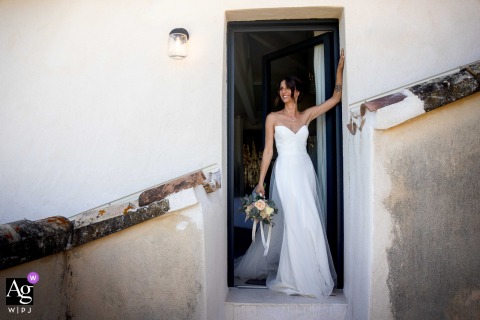 At the Domaine des Patras in France, the bride is photographed standing in front of a door, with a strong diagonal line from an outside handrail cutting across the frame.