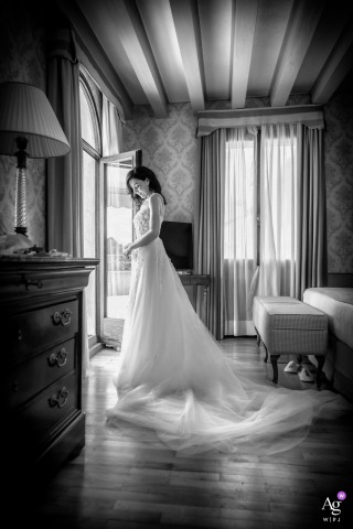 Asolo, Italy, provides the setting for an intimate hotel room portrait of the bride, who is captured in a quiet look admiring her gown at the end of her preparations.