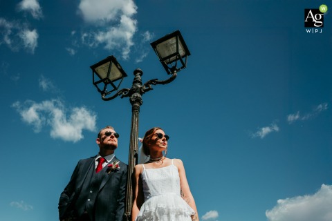 In the charming village of Calvisson, the wedding couple leans casually against a classic street lamp, creating a stylish and romantic urban portrait in the Hérault region.