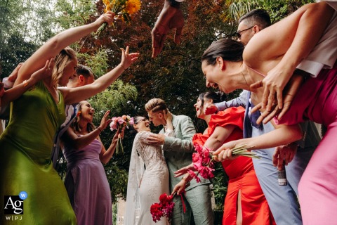 Chateau les Hauts, wedding venue — Bridesmaids and groomsmen frame the kissing couple at the end of a tunnel in an action-filled scene, creating a dynamic and celebratory wedding portrait.