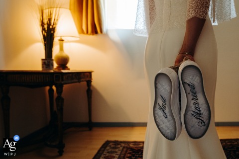 In Tour de Diors - Indre, the bride stands holding her sneakers, revealing the rubber bottoms of the shoes marked with the words "Just Married" on her wedding day.