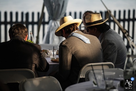 Sunlight warmly illuminates the intricate texture of a guest's tie, capturing a quiet, artistic detail against the backdrop of the celebratory wedding reception at the historic House of Seven Gables.