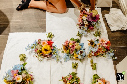 Focusing on the day's preparation, a bridesmaid carefully arranges the wedding bouquets on a soft towel at the Marriott Delta Hotel in Preston, located in the UK.