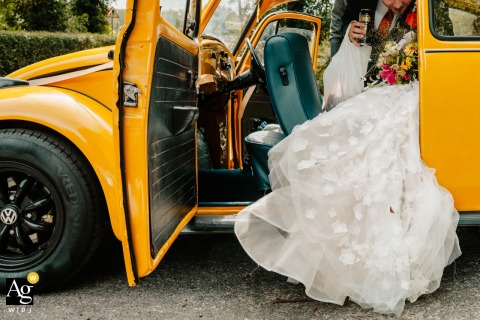 An artistic detail shot captures the bride and groom getting into a vibrant yellow vintage VW beetle outside a classic chapel in Stockport, UK.