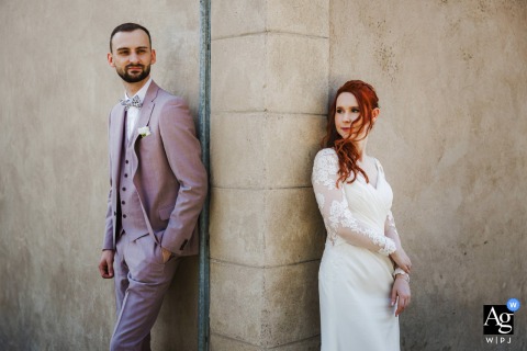Metz Chapel: The couple poses on opposite sides of a stone pillar at the chapel’s corner, the groom looking toward the camera with a subtle smile while the bride gazes thoughtfully into the distance, creating a contemplative wedding photo.