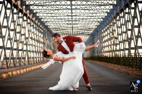 Pont Eiffel, Cubzac-les-Ponts, near Bordeaux — The couple shares a playful dip and kiss within the symmetrical lines and framing of the bridge, creating a fun and dynamic wedding portrait.