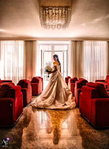 Genova Nervi — The bride is captured in a solo indoor portrait, standing among red sofas and ready for her “yes,” creating an elegant and anticipatory wedding image.
