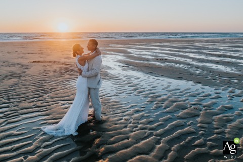 The wedding couple shares a romantic portrait session on the sandy shores of Lacanau Océan at sunset, capturing the golden light along the scenic coast of Gironde.