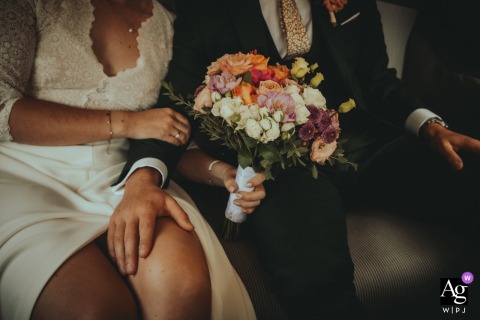 Bride and groom share a quiet moment together inside a car in France, with the bridal bouquet resting prominently on the bride's lap, symbolizing their love.