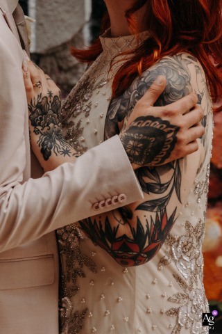 A close-up artistic detail shows the bride and groom's intertwined, tattooed hands resting together, symbolizing their commitment on their wedding day in Orléans Street, France.