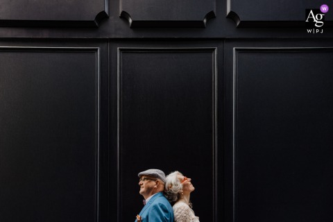 Nantes, France — The bride and groom stand back to back in profile, symmetrically framed and small at the bottom of the image against a black background, creating a dramatic and minimalist wedding portrait.