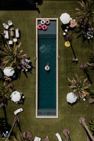 Château du Parc Saint Lambert la Potherie, France, presents an artistic aerial view of the stately reception venue's shimmering pool and surrounding grounds set up for the wedding brunch, offering a broad scene setter of the elegant day.