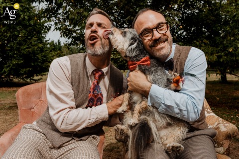 Gîte de la Maronnière, Nantes, France — The newlyweds sit side by side, smiling as their dog licks his face, capturing a joyful and playful wedding portrait at the reception venue.