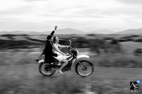 Domaine Etxezahar, Bardos, France — The bride drives a vintage motorcycle with the groom as her passenger, captured in motion blur for an energetic and playful wedding portrait at the venue.