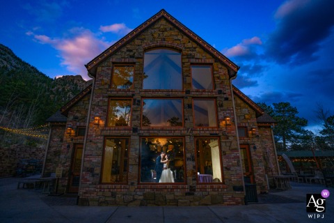 Fort Collins, Colorado — The bride and groom share a romantic portrait session indoors during their wedding reception, with the photographer capturing the intimate exchange from outside the structure for a unique perspective.