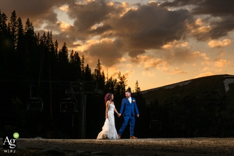 Following their ceremony at a Colorado ski resort, the bride and groom take a romantic sunset walk together through the high-altitude landscape of the Rocky Mountains.