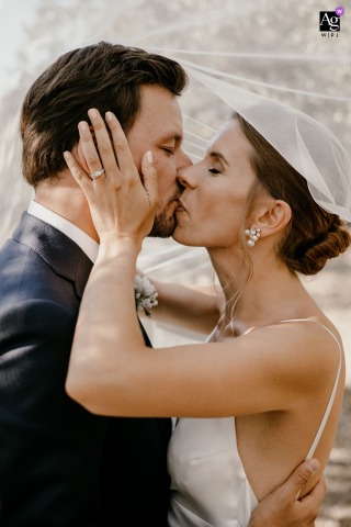 Mas d'Arvieux en Provence — In a tight vertical shot under the bride’s veil, the couple shares a passionate kiss, capturing intimacy and romance on their wedding day.