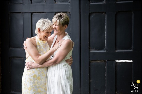 St Albans Register Office, Hertfordshire — Two brides in white share in laughter during couple portraits, celebrating their civil partnership outside the register office.