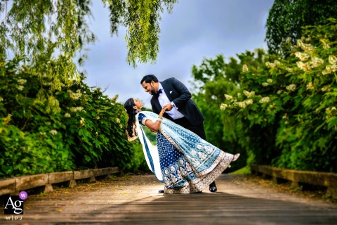 Romantic Dip Couple Wedding Portrait Surrounded By Greens At Talamore Country Club Philadelphia Talamore Country Club, Philadelphia — Surrounded by lush greens, the couple shares a romantic dip, beautifully lit in a symmetrical portrait that blends nature with the celebration of tradition and culture.