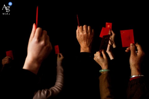 In Zhanjiang, Guangdong, the groom and others hold vibrant red envelopes prepared as traditional tokens of goodwill for the bride's family and friends just before he enters her home.
