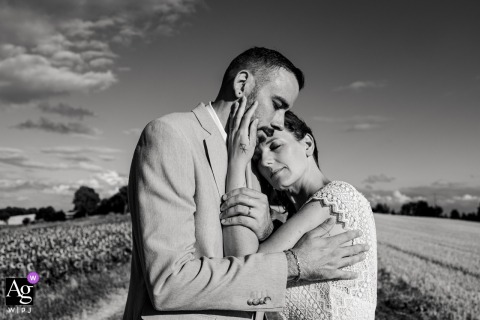Auch, France — The couple embraces in the middle of the fields under an open sky, their hands and arms wrapped around each other, captured in a black-and-white wedding portrait full of intimacy and emotion.